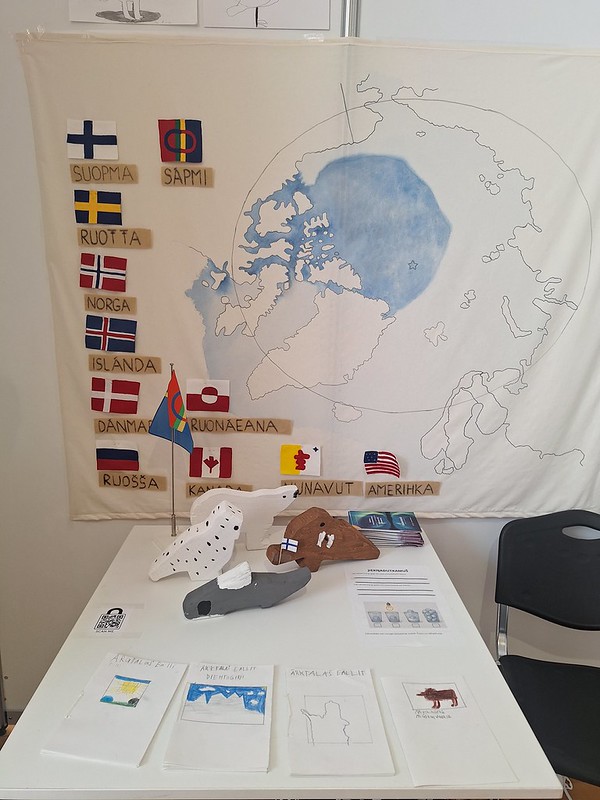 Valokuvassa arktisen alueen kartta, maiden lippuja ja lasten tekemiä projektitöitä.