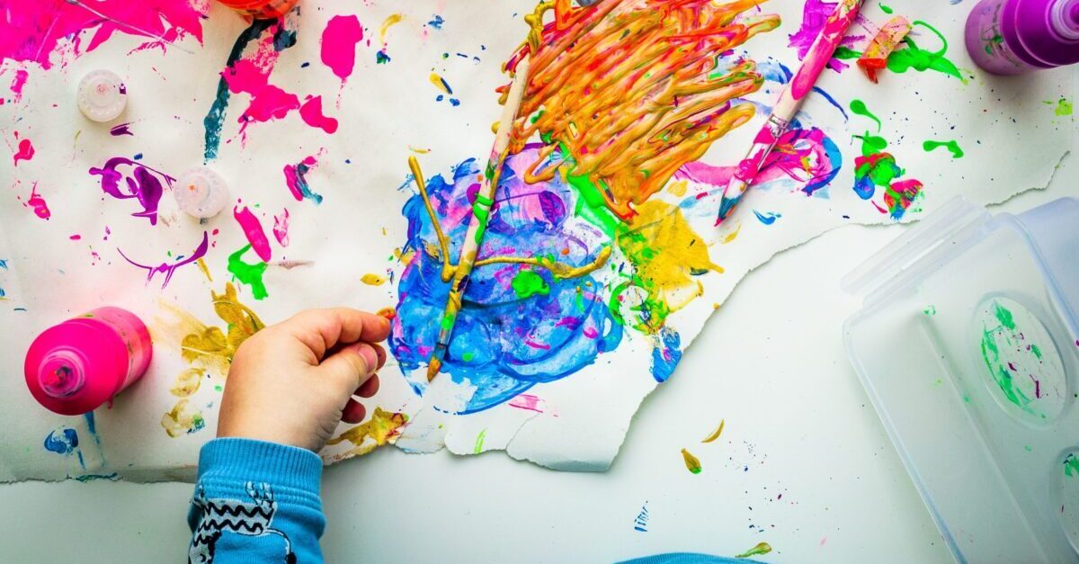 Lapsen käsi ja luovaa maalausta väreillä.
