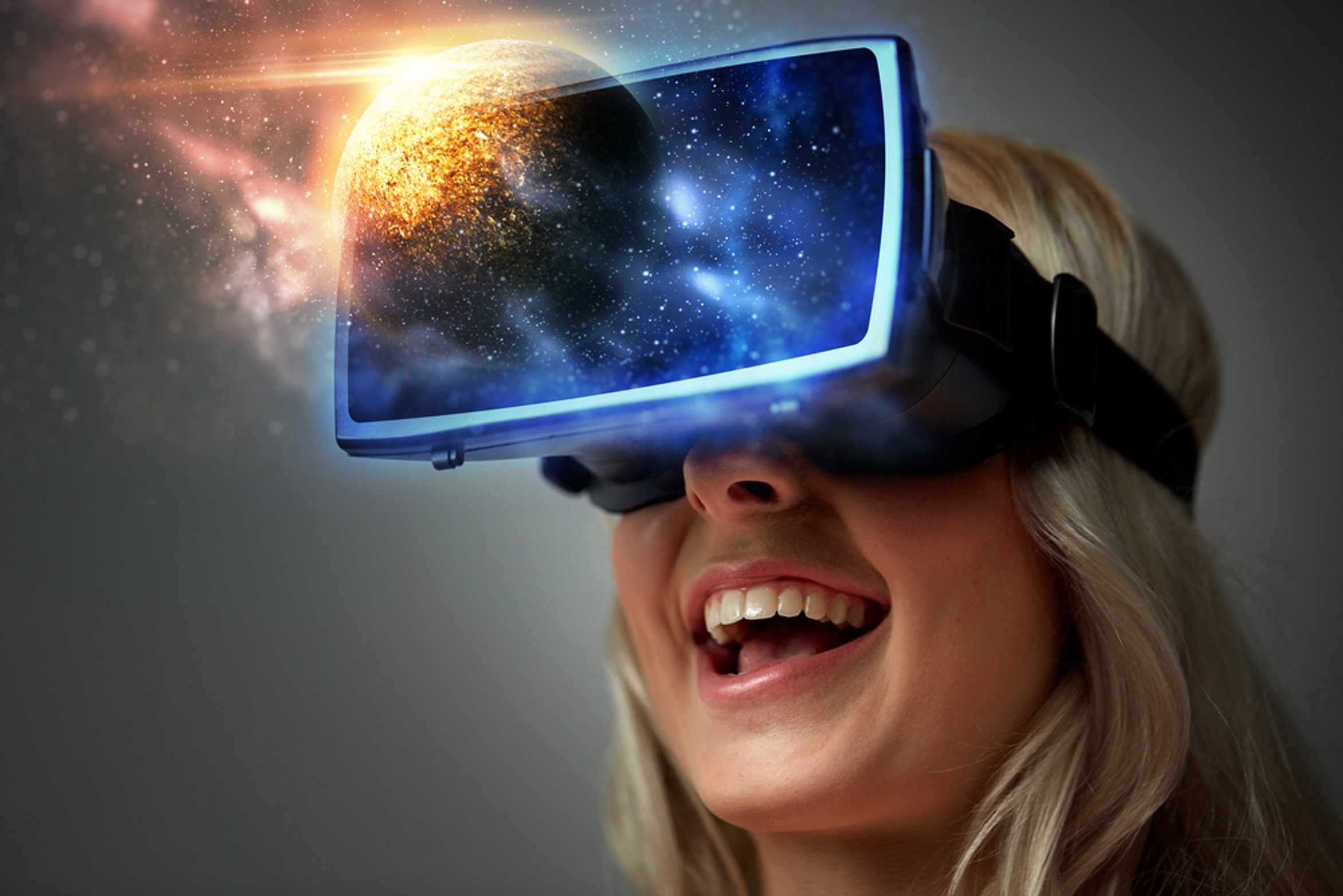 Kuva innostuneesta nuoresta tytöstä, jolla on päässään vr-lasit. Vr-laseista heijastuu ulospäin avaruus.