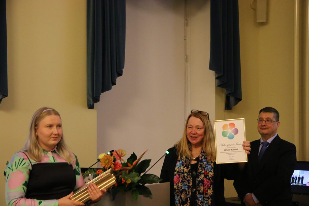 Naispuolinen henkilö joka palkitsee opettajia diplomeilla.