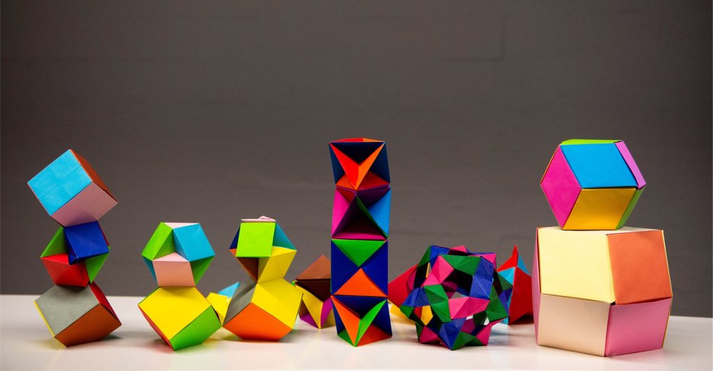 Kuvassa värikkäitä origami-kappaleita, jotka on taiteltu LUMATIKKA-täydennyskoulutusohjelman matikkataidetyöpajassa.