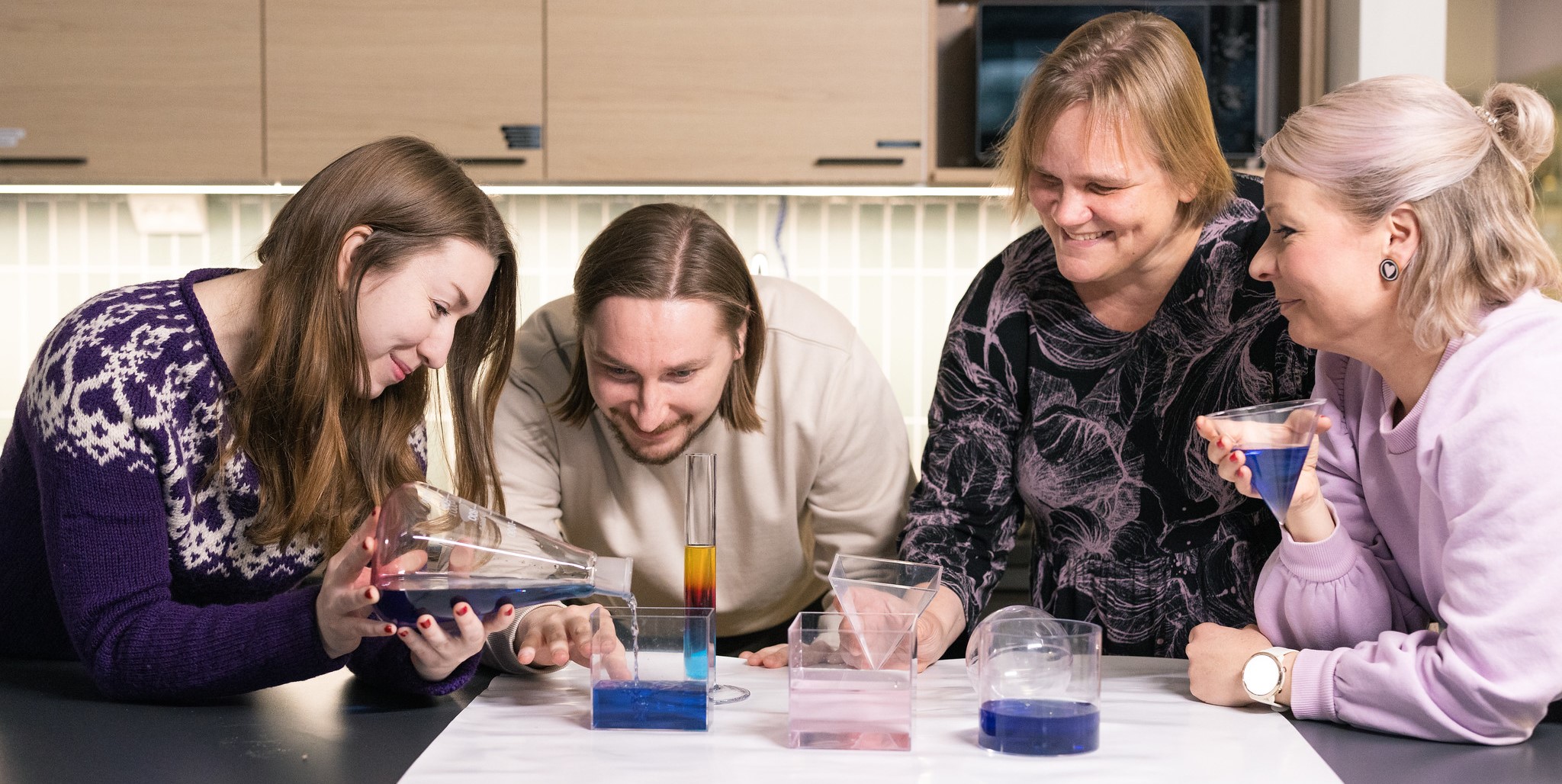 Kuvassa eri-ikäiset opettajat tekevät tutkimusta kemian välineillä yhdessä ja hymyssä suin. Kuvaaja: Konsta Lähde / Kuvalähde Oy