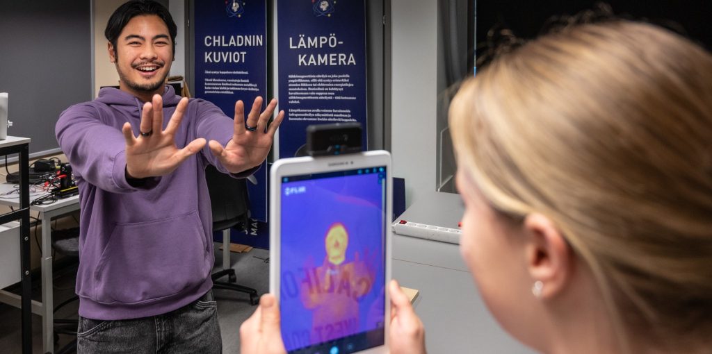 Kuvassa lukiolaiset leikkivät lämpökameralla.