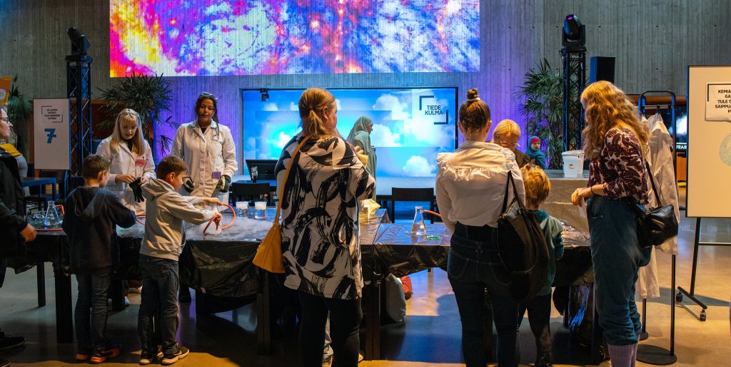 Kuva tiedetapahtumasta, jonne on osallistunut perheitä.